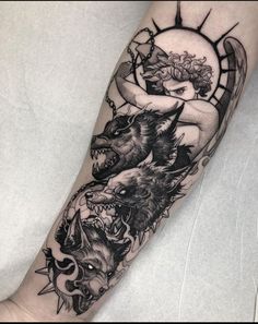 an arm with some tattoos on it and two wolfs in the middle of it