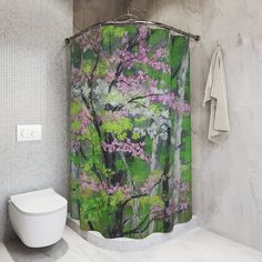 a bathroom with a shower curtain that has pink flowers on it and green trees in the background