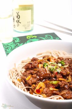 a white bowl filled with noodles and meat