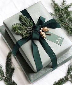 two wrapped presents with green ribbon and pine cones