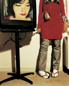 a woman standing in front of a television with her hands on her hips and eyes closed