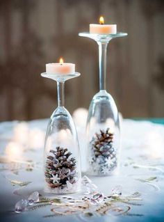 two wine goblets with pine cones in them on a table covered in snow