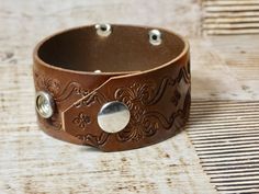 "This listing is for the #2 pictured bracelet. I also can do a custom bracelet- I have numbers 1-8 (depending on sales, message me and i can tell you what I have left). The bracelet is Brown leather and measures 1 1/8\" in width. The bracelet has two snaps, one at 7\" and one at 8\". It will fir most average size wrists. Check out many other bracelets in my store. Silver number measures 1 3/8\" X 1 1/8\". This piece is not sterling but has a great antique silver look. The tags are from old locke Adjustable Leather Bracelet With Custom Hardware As Gift, Adjustable Leather Bracelet With Custom Hardware, Brown Concho Bracelets As Gift, Adjustable Stamped Leather Cuff Bracelet, Adjustable Concho Cuff Bracelet Gift, Brown Bracelets With Custom Hardware For Gift, Brown Stamped Cuff Bracelets, Brown Stamped Cuff Bracelet, Hand Tooled Cuff Bracelets As A Gift