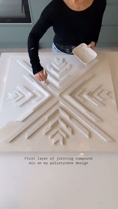 a woman is working on a sculpture in the shape of a snowflake with words written below it