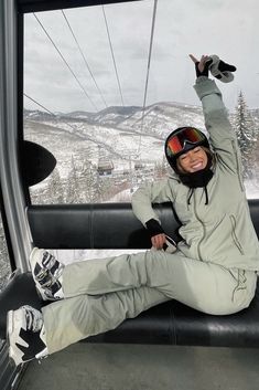 a woman sitting on the side of a ski lift with her arms in the air