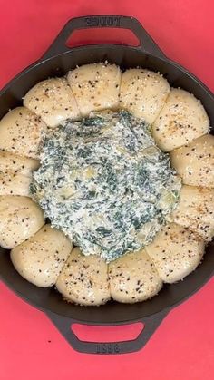 a pan filled with bread and spinach on top of a red table