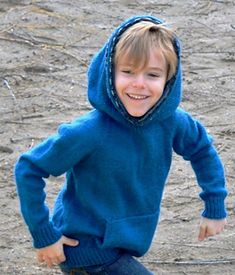 a young boy in a blue hoodie is playing with a frisbee on the ground