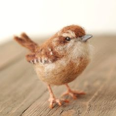 a small brown bird sitting on top of a wooden table