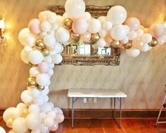 white and gold balloons are hanging from the ceiling in front of a table with a mirror on it