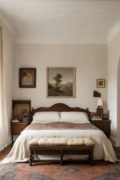 a bedroom with a large bed and paintings on the wall