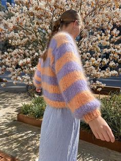 a woman in a striped sweater walking down the street with her hand on her hip