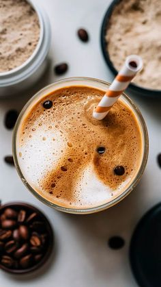 there is a drink with a straw in it on the table next to some coffee beans