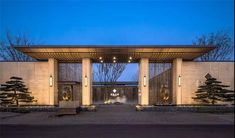 an entrance to a building with trees and lights on the outside, in front of it