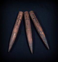 three wooden arrows with designs on them are shown next to each other in the dark