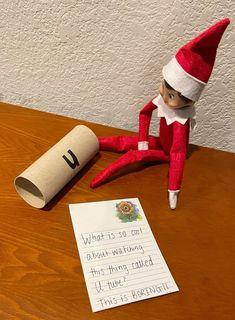 an elf sitting on top of a table next to a roll of paper