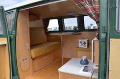 the interior of a small camper with wood paneling and green walls, including windows