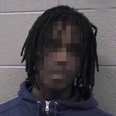 a man with dreadlocks wearing a blue hoodie in front of a wall