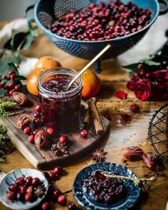 cranberry sauce in a jar on a cutting board surrounded by other fruit and vegetables