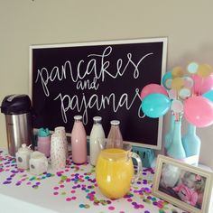 a table topped with balloons, confetti and other items next to a sign