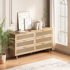 a living room with a plant and some pictures on the sideboard in front of an open window