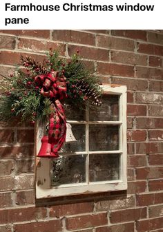 an old window is decorated with red and green christmas wreaths, pine cones, and bells