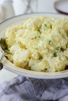 a white bowl filled with potato salad on top of a table