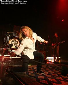 a woman in white shirt and black pants on stage