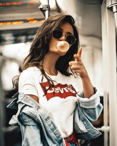 a woman wearing sunglasses blowing bubbles on her nose