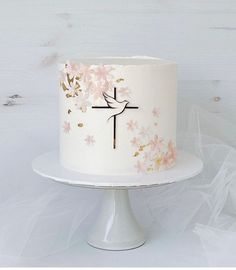 a white cake with pink flowers and a cross on top