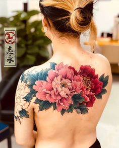 the back of a woman's body with flowers tattooed on her upper and shoulder