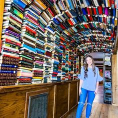 a woman standing in front of a large amount of books