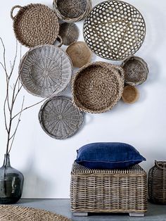 woven baskets are hanging on the wall next to a blue cushion and vase with flowers in it