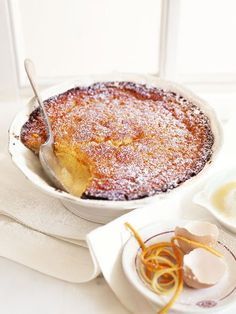 a dessert dish with powdered sugar and orange peels on the plate next to it