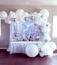 a table topped with white and silver balloons