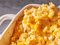 a spoon full of macaroni and cheese being lifted from a casserole dish