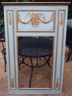 an ornately painted cabinet with a black table and chairs in front of it on a deck