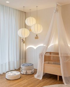 a baby's room with white drapes and round lights hanging from the ceiling