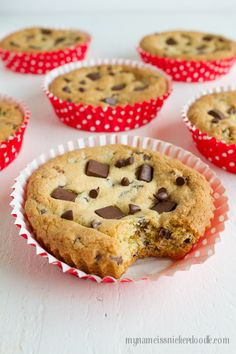 chocolate chip muffins in red and white paper cups on a white table top