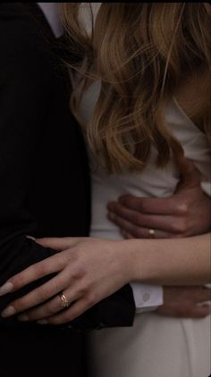 a close up of two people hugging each other with their arms around one another while wearing wedding rings