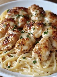 pasta with chicken and parmesan cheese sauce on a white plate sitting on a wooden table