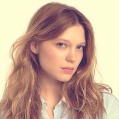 a woman with long hair is posing for the camera while wearing a blue button up shirt