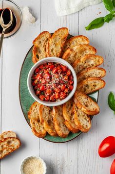 a plate with bread slices, tomato salsa and basil sprinkled on top in a bowl