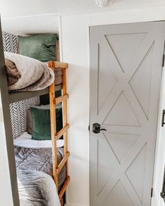 a white door in the corner of a room next to a bunk bed with pillows and blankets on it