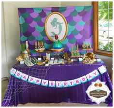 a purple table topped with cake and cupcakes