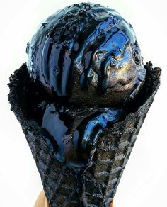 an ice cream cone with blue icing on it's top is being held up to the camera