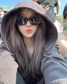 a woman wearing sunglasses and a hoodie taking a selfie