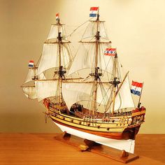 a model ship on a wooden table with two flags flying from it's sails