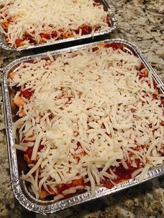 two pans filled with pizza covered in cheese on top of a granite countertop