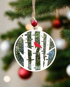 a christmas ornament hanging from a tree decorated with white birch trees and a red bird