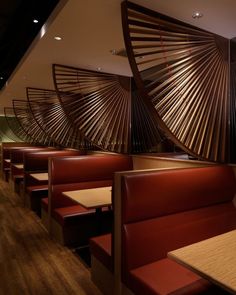 the interior of a restaurant with red booths and wooden tables in front of an artistic wall